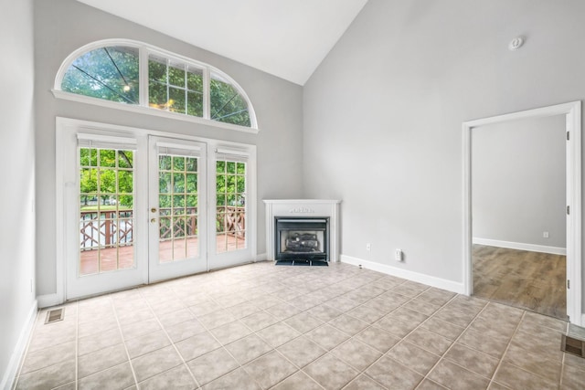 unfurnished living room with high vaulted ceiling and light tile patterned floors