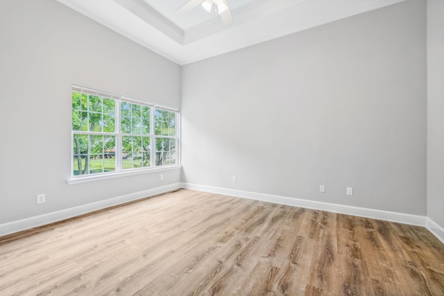 unfurnished room featuring light wood-type flooring, ceiling fan, a raised ceiling, and ornamental molding