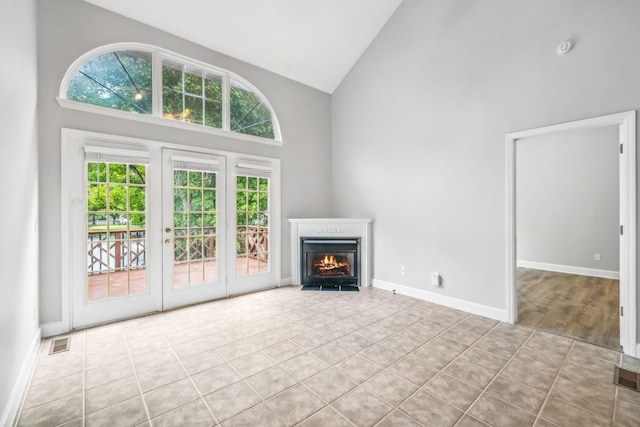 unfurnished living room featuring high vaulted ceiling and light tile patterned flooring