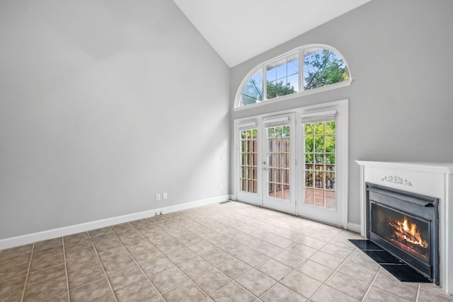 unfurnished living room with french doors, high vaulted ceiling, and light tile patterned floors