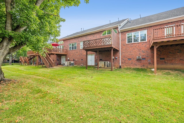 rear view of house featuring a deck, a lawn, and central AC