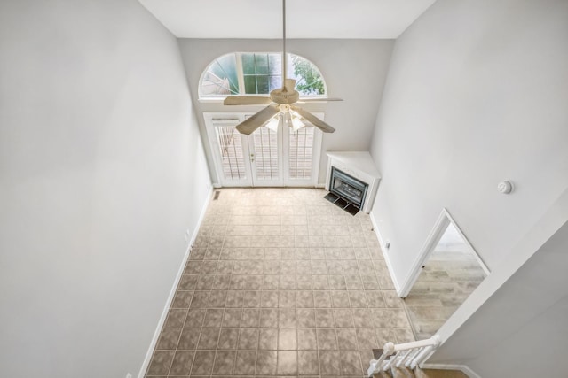 unfurnished living room featuring ceiling fan and a towering ceiling