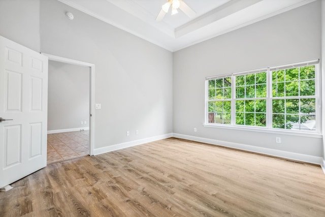 spare room featuring ceiling fan, light hardwood / wood-style flooring, and a tray ceiling