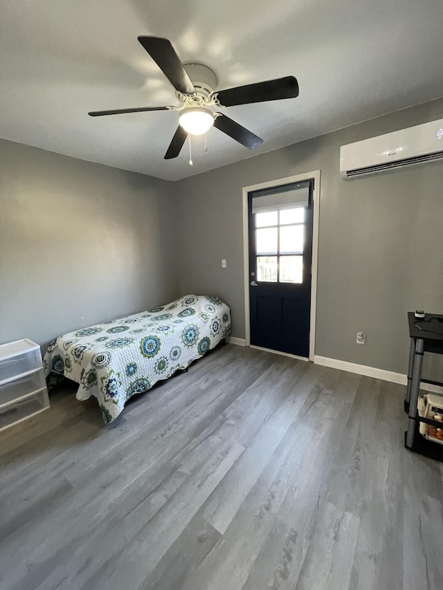 bedroom featuring ceiling fan, hardwood / wood-style flooring, and an AC wall unit