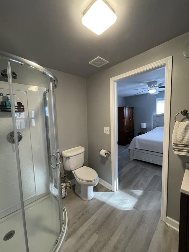 bathroom featuring hardwood / wood-style floors, toilet, an enclosed shower, and ceiling fan