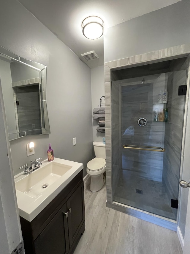 bathroom with hardwood / wood-style floors, toilet, an enclosed shower, and vanity