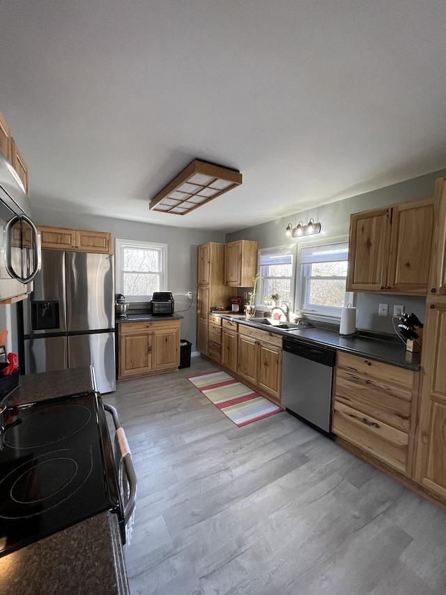 kitchen with sink, a wealth of natural light, light hardwood / wood-style flooring, and appliances with stainless steel finishes