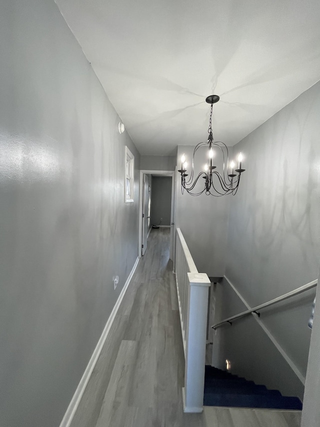 stairway with wood-type flooring and a notable chandelier