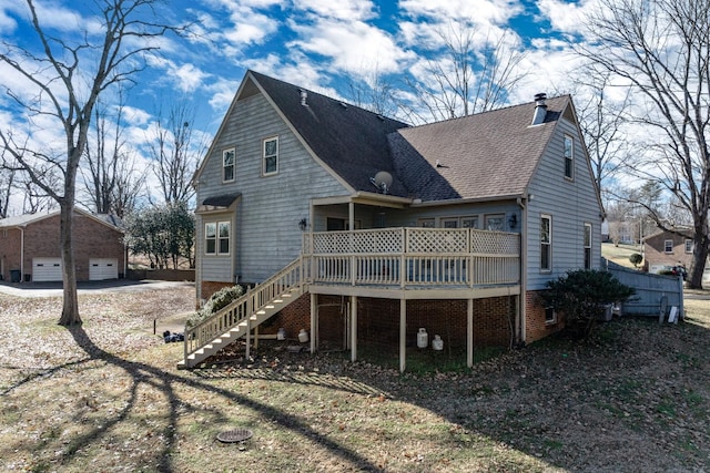 rear view of property featuring an outbuilding, a garage, and a deck