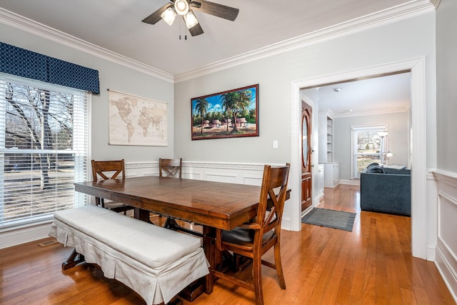 dining room featuring ornamental molding, built in features, ceiling fan, and light wood-type flooring