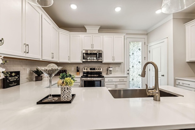 kitchen featuring appliances with stainless steel finishes, white cabinetry, decorative backsplash, sink, and ornamental molding