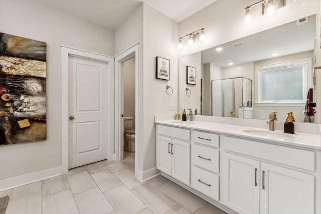 bathroom featuring vanity, a shower with shower door, tile patterned floors, and toilet