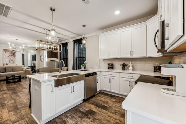 kitchen featuring white cabinetry, sink, kitchen peninsula, pendant lighting, and stainless steel appliances