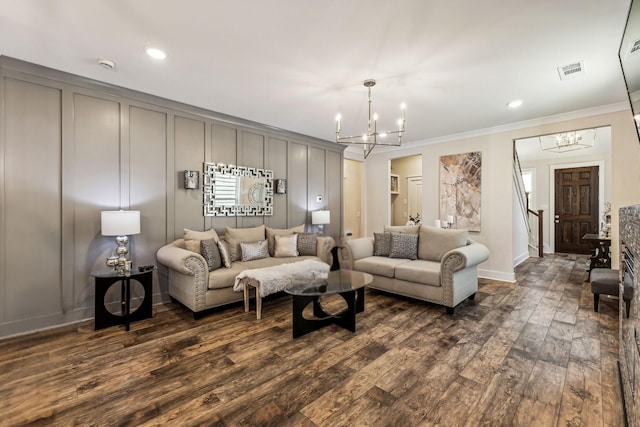 living room featuring dark wood-type flooring, a chandelier, and ornamental molding