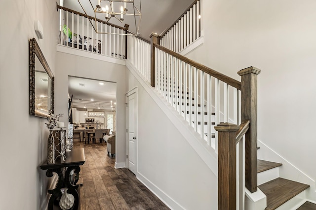 staircase featuring a high ceiling, wood-type flooring, and a notable chandelier