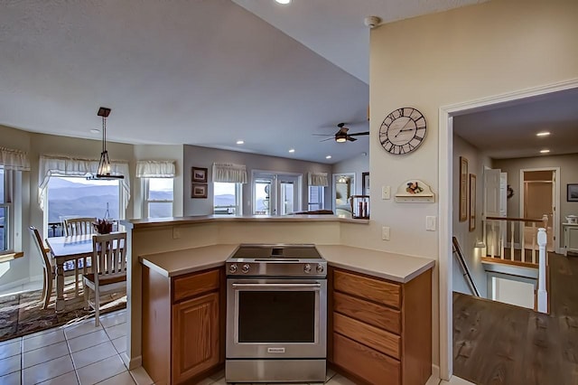 kitchen with ceiling fan, stainless steel range, light tile patterned flooring, vaulted ceiling, and kitchen peninsula