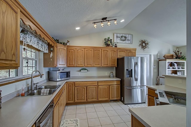 kitchen featuring sink, light tile patterned floors, stainless steel appliances, a textured ceiling, and vaulted ceiling