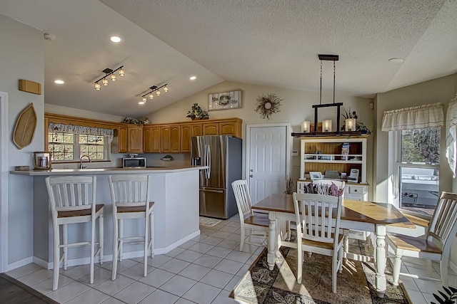 kitchen featuring stainless steel refrigerator with ice dispenser, lofted ceiling, a wealth of natural light, and light tile patterned flooring