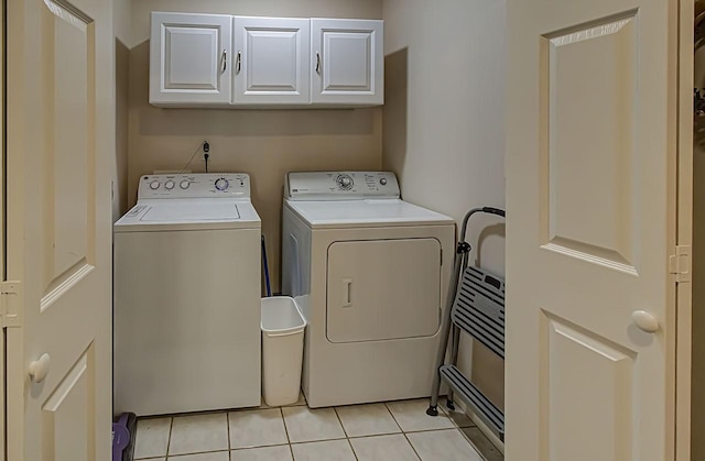 laundry area featuring cabinets, light tile patterned floors, and washing machine and clothes dryer