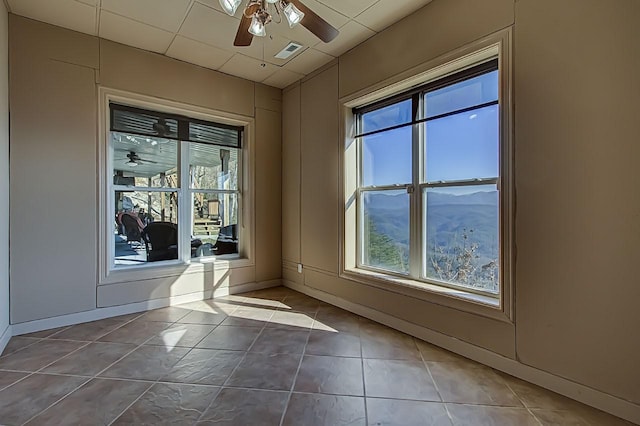 tiled empty room with ceiling fan and a mountain view