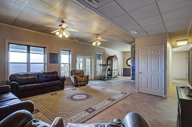 tiled living room featuring french doors, ceiling fan, crown molding, and a drop ceiling