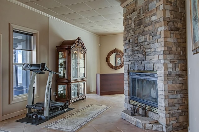 workout room with crown molding, light tile patterned flooring, and a fireplace