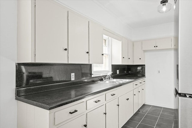 kitchen with sink, dark tile patterned flooring, white cabinets, and tasteful backsplash