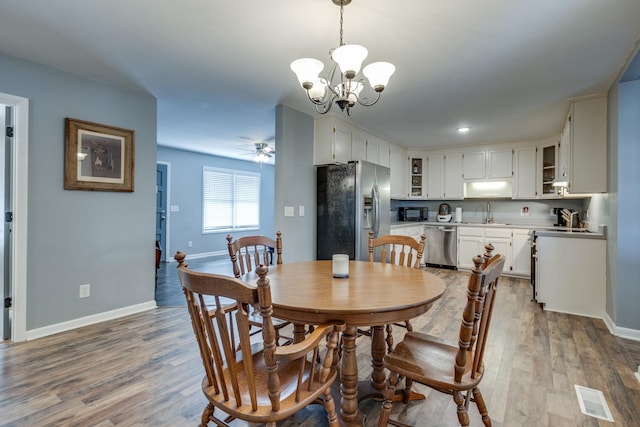 dining area featuring sink, ceiling fan with notable chandelier, and light hardwood / wood-style flooring