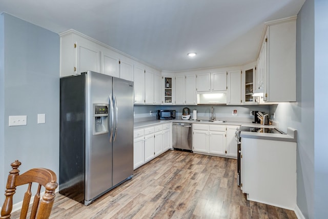 kitchen featuring sink, white cabinets, appliances with stainless steel finishes, and light wood-type flooring