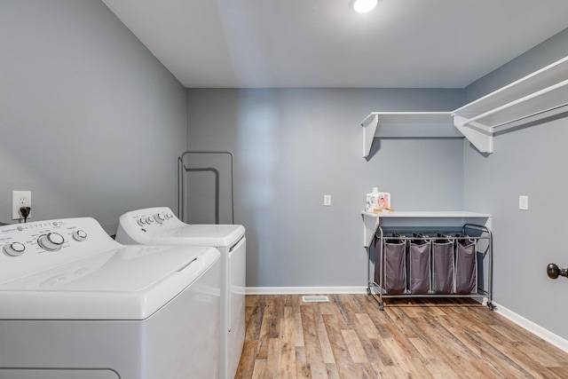 clothes washing area with washer and clothes dryer and hardwood / wood-style floors