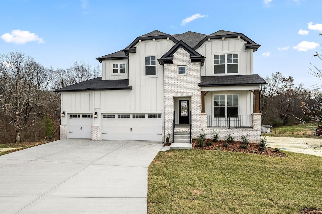 view of front of property with a garage, a front lawn, and covered porch