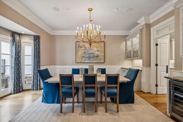 dining area featuring crown molding, light hardwood / wood-style floors, a notable chandelier, and beverage cooler