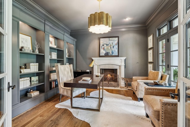 home office featuring built in shelves, wood-type flooring, a chandelier, and crown molding