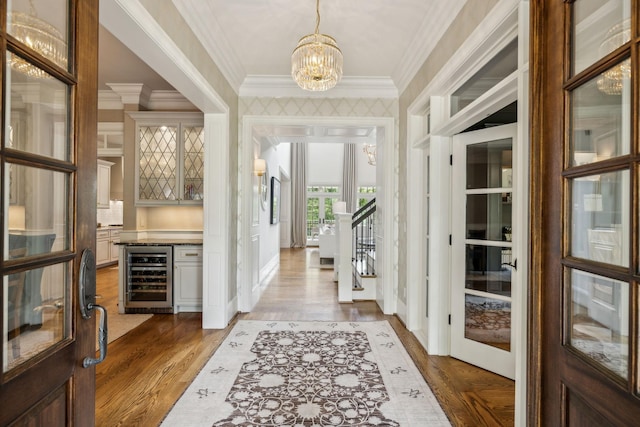 entryway with crown molding, hardwood / wood-style flooring, wine cooler, and an inviting chandelier