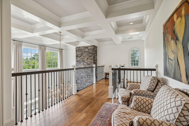 corridor with coffered ceiling, beamed ceiling, ornamental molding, and plenty of natural light