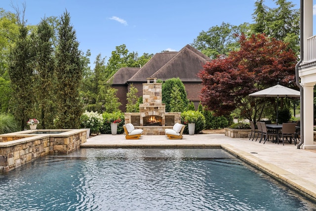 view of pool with an in ground hot tub, a patio area, and an outdoor stone fireplace