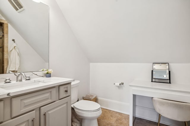 bathroom with toilet, vanity, and lofted ceiling