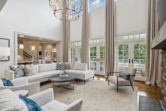 living room featuring a towering ceiling, a notable chandelier, and french doors