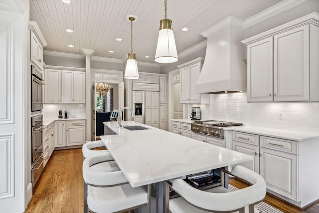 kitchen with white cabinets, a kitchen island with sink, tasteful backsplash, and custom range hood