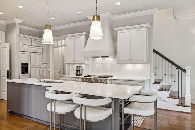 kitchen with decorative light fixtures, white cabinetry, custom range hood, and tasteful backsplash