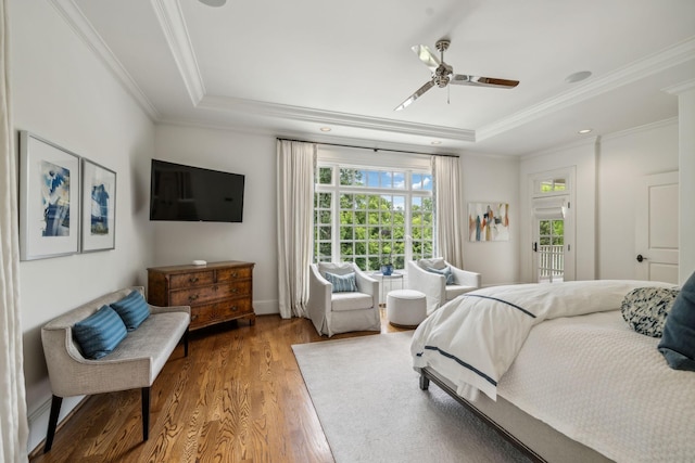 bedroom featuring ceiling fan, hardwood / wood-style floors, ornamental molding, and a raised ceiling