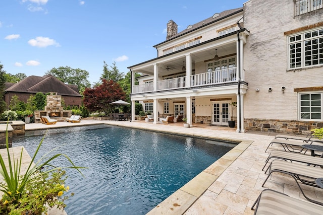 view of swimming pool with a patio, an outdoor stone fireplace, ceiling fan, and french doors