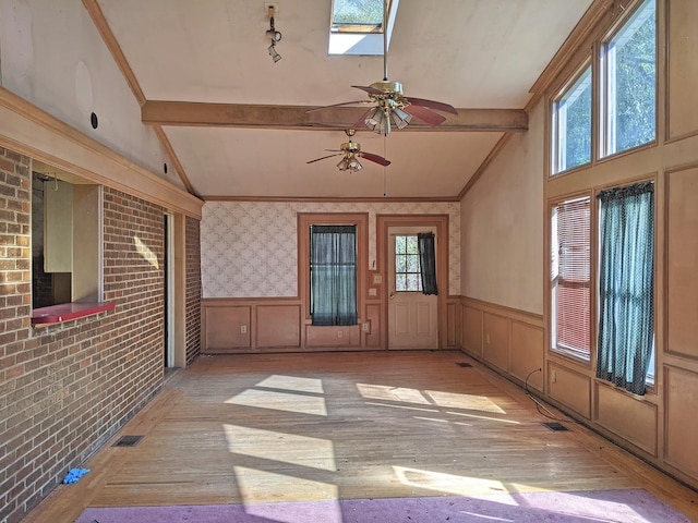 unfurnished sunroom with ceiling fan, plenty of natural light, and lofted ceiling with beams