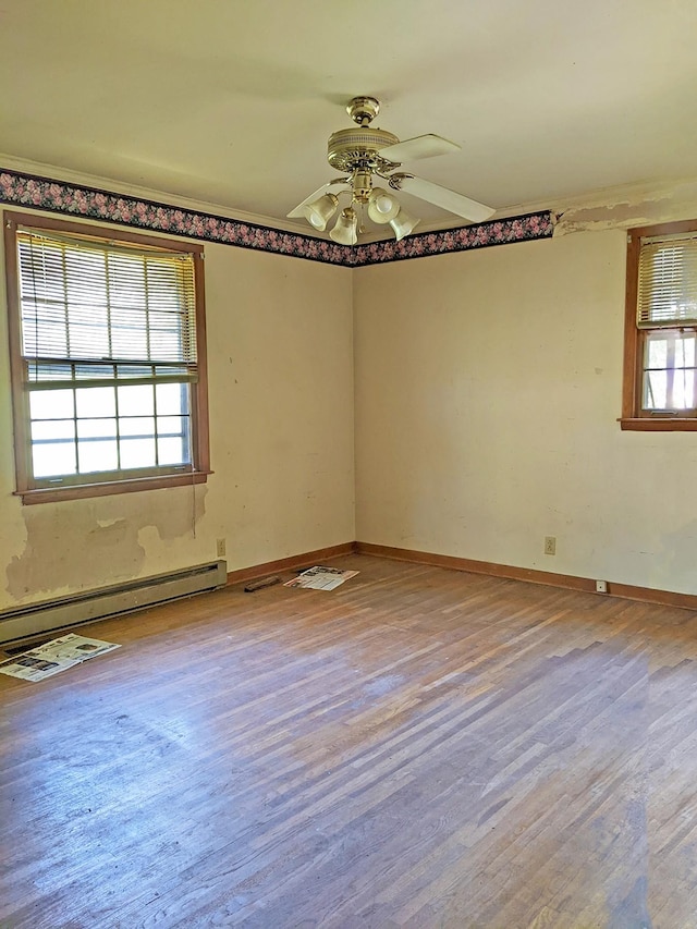 empty room with ceiling fan, baseboard heating, and wood-type flooring