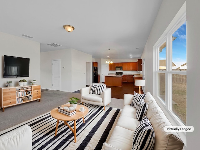 carpeted living room with sink and a notable chandelier