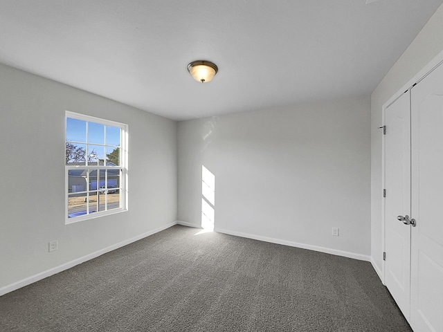 unfurnished bedroom with dark carpet and a closet