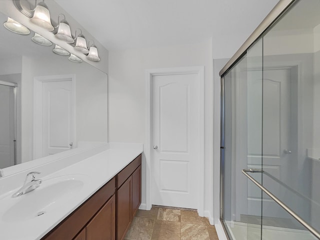 bathroom featuring a shower with shower door and vanity