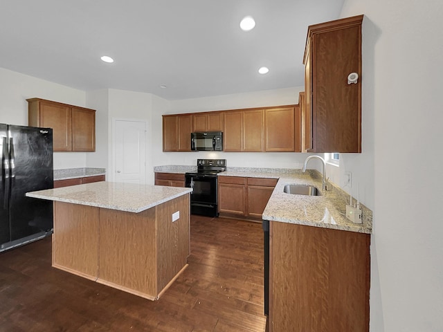 kitchen with black appliances, a center island, light stone countertops, sink, and dark hardwood / wood-style flooring