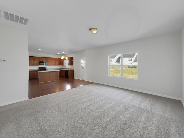 unfurnished living room featuring dark carpet and a chandelier