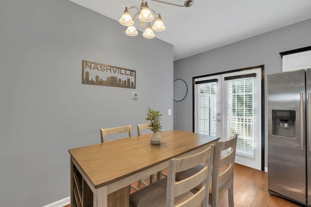 dining area featuring hardwood / wood-style floors, a notable chandelier, and french doors